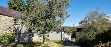 A stone building with a paved driveway and a tree in front.