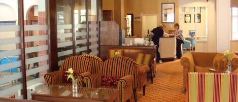 A hotel lobby with striped sofas, a reception desk, and a patterned carpet.