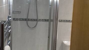 Een douchecabine met glazen wanden, een handdouche, een wit toilet en een vloer van marmertegels.