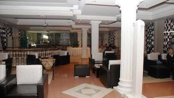 A hotel lobby with seating areas, a reception desk, and a bar.