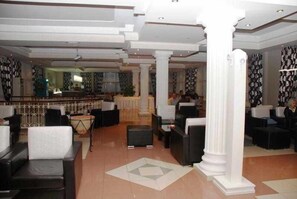 Um saguão de hotel com áreas de estar, balcão de recepção e bar.