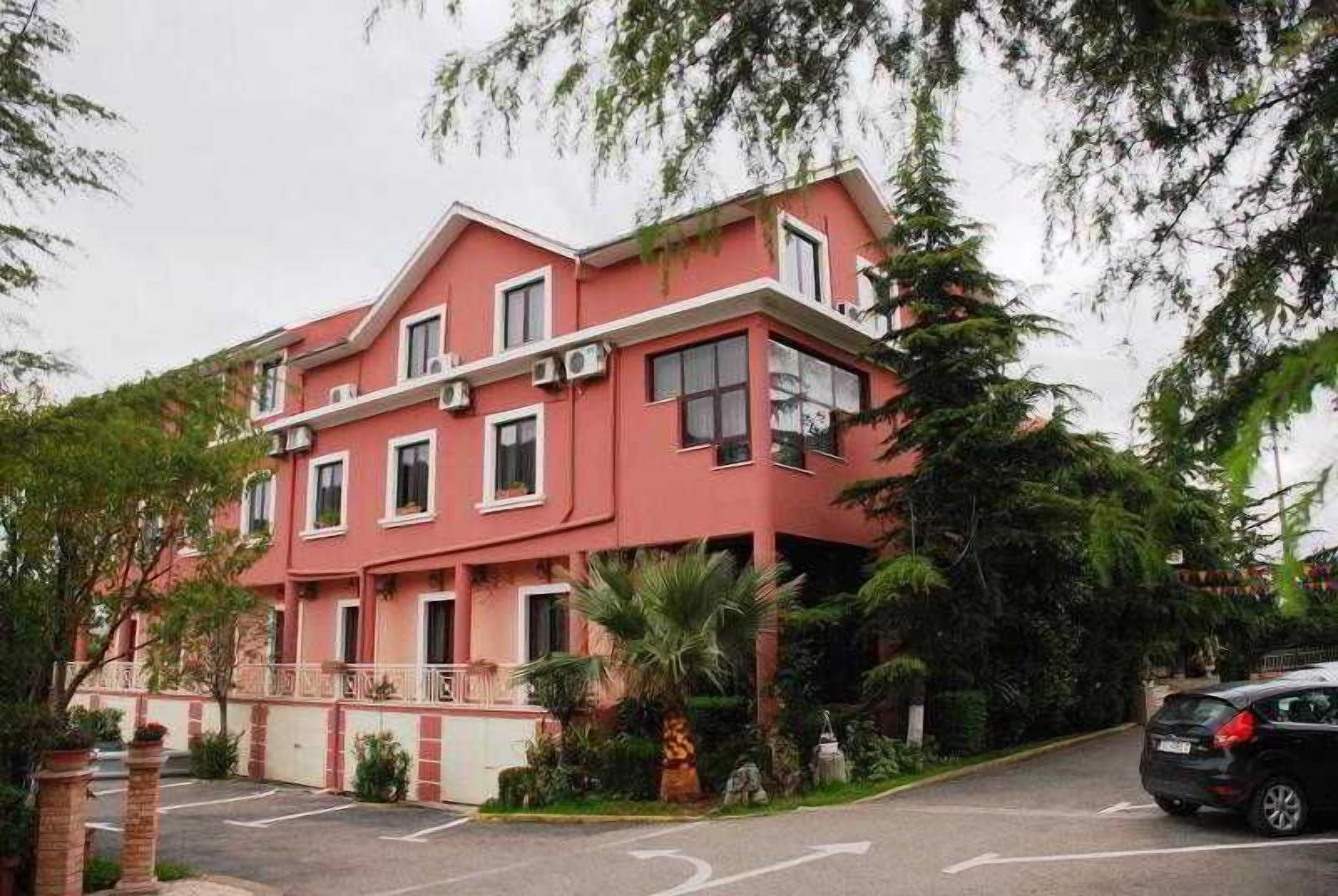 A multi-story building with a red facade, multiple windows, and a gated entrance.