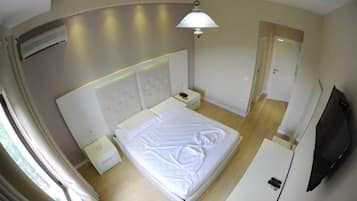 Een hotelkamer met een bed, nachtkastjes, een flatscreen televisie en een deur naar een andere kamer.