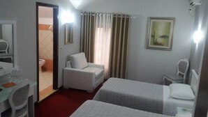 A hotel room with a bed, a chair, a desk with a mirror, and a window with curtains. - Univers (Elbasan)