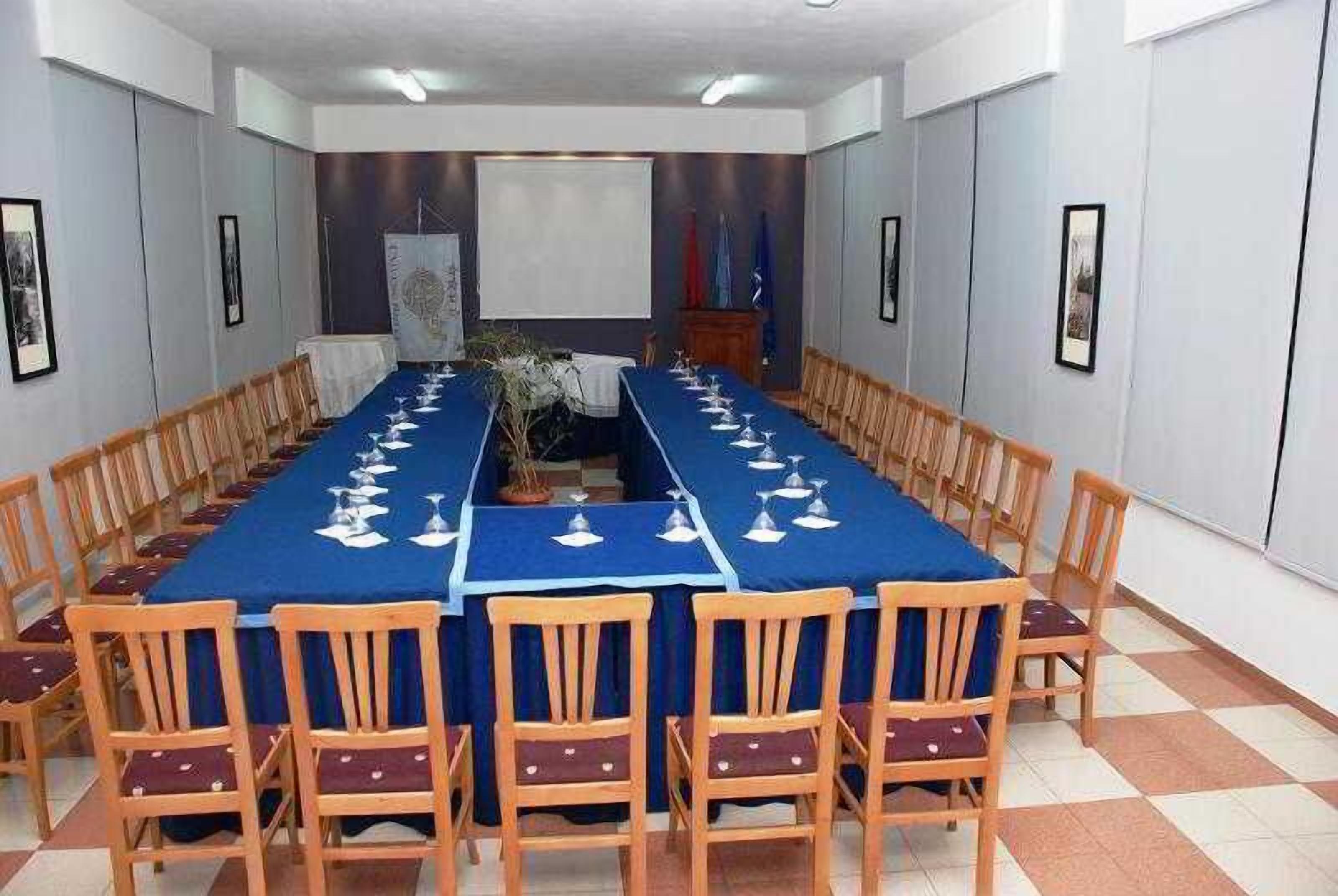 Une salle de conférence avec une longue table, des chaises et un pupitre.