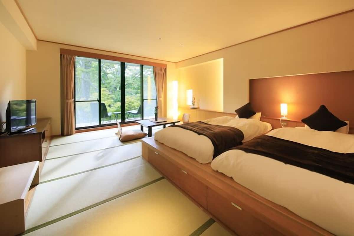 Habitación de hotel con una cama grande, un escritorio, un televisor y una ventana con cortinas.
