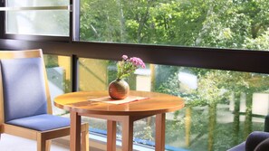 A room with a wooden table, a chair, and a window with a view of trees.