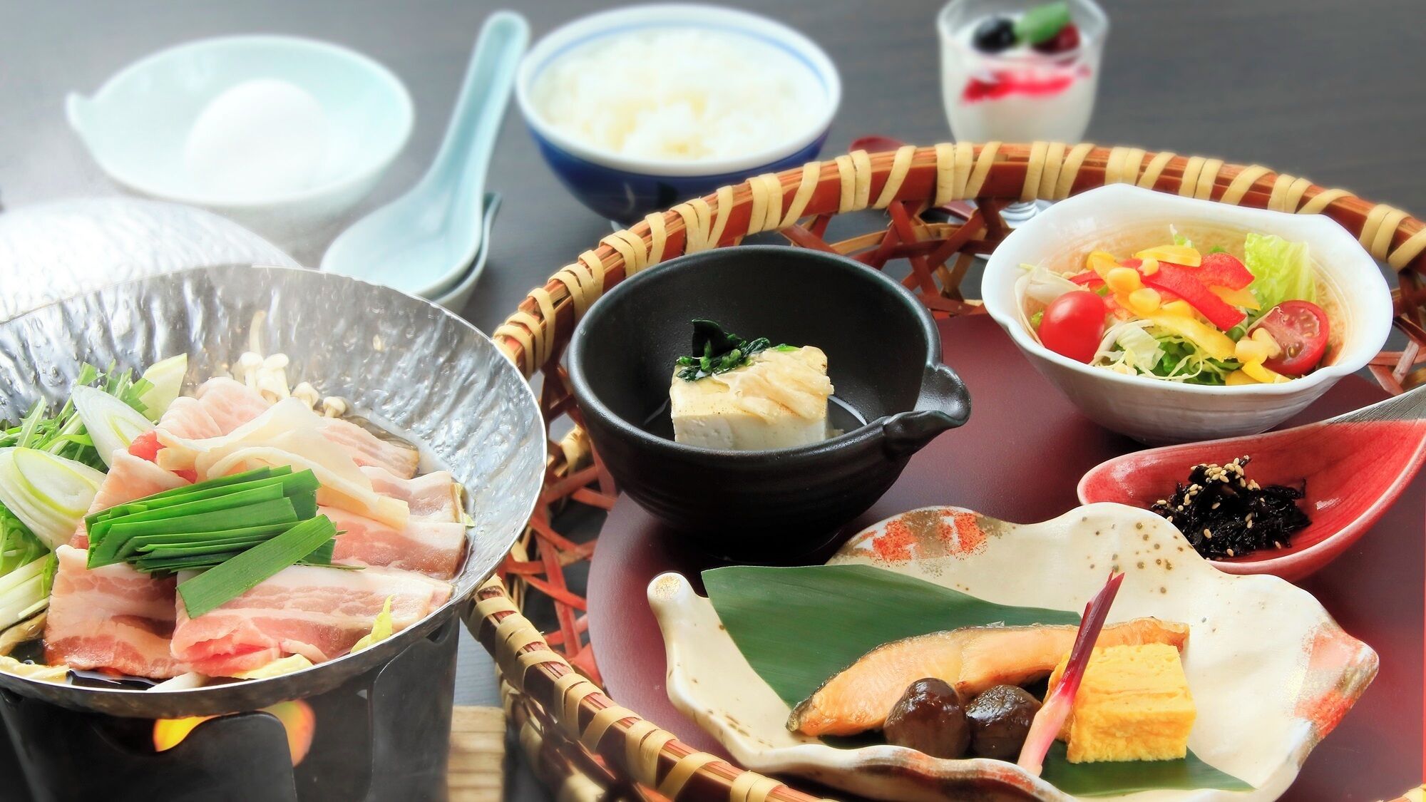 Diversos platos en recipientes tradicionales, un cuenco pequeño de arroz y una taza de té.