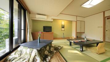 A traditional Japanese-style room with tatami flooring, a low table, and a television on a wooden cabinet.
