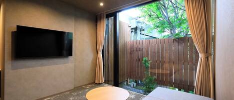 A room with a flat-screen TV mounted on the wall, a round table, and a sofa.