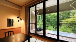 A room with a large sliding glass door leading to an outdoor deck with a hot tub. - Okunikko Hotel Shikisai (Nikko)