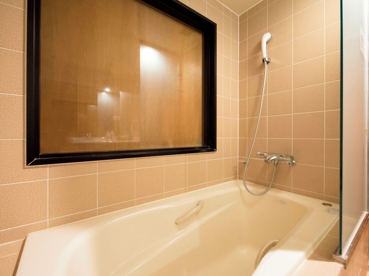 Een badkamer met een badkuip, douche en raam.