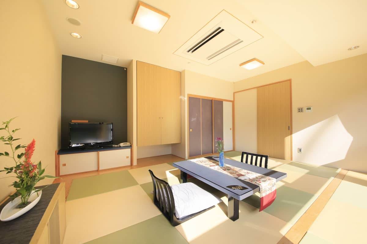 Una sala de estar moderna con suelo de tatami, una mesa baja, un sofá y una televisión.