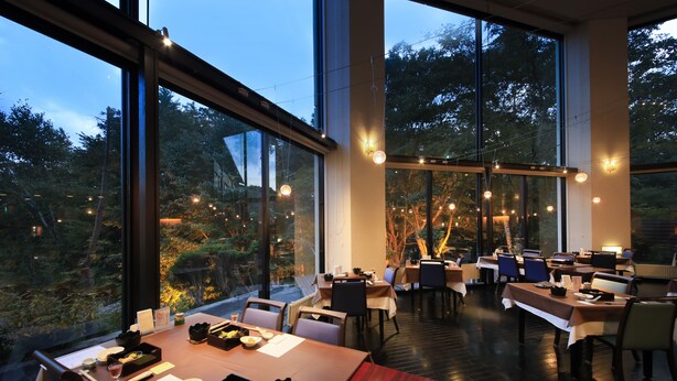 A restaurant with multiple tables and chairs, large windows, and string lights. - Okunikko Hotel Shikisai (Nikko)