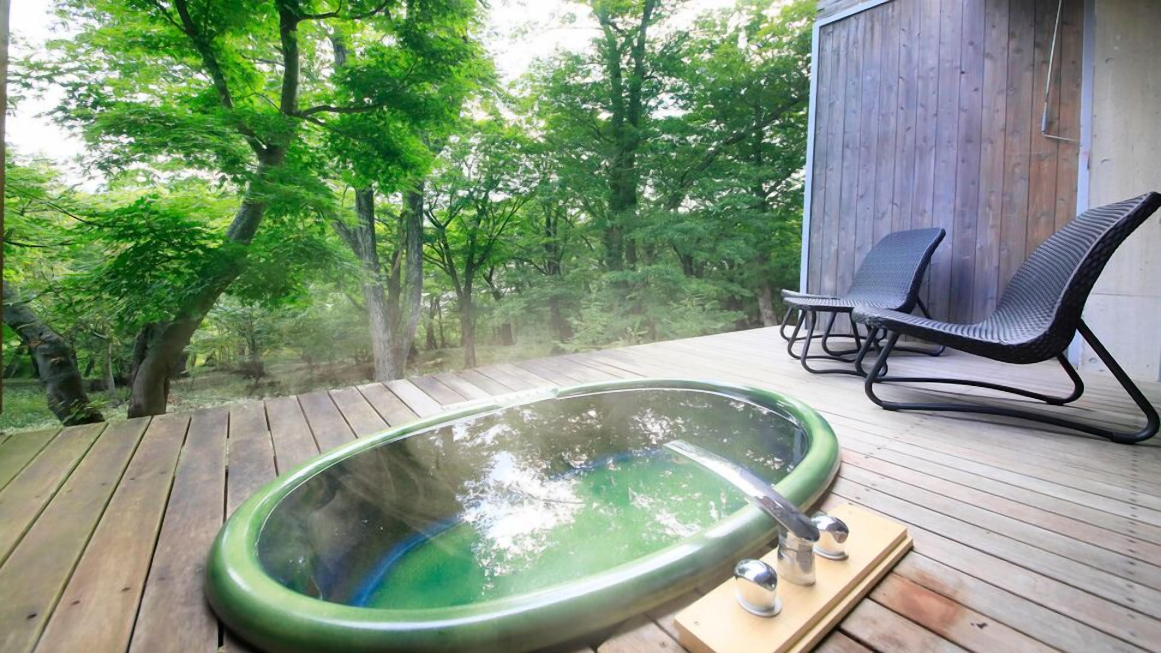 Ein Whirlpool auf einer Holzterrasse mit Blick auf einen Wald.