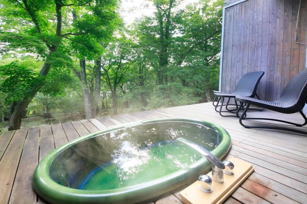 Un jacuzzi en una terraza de madera con vista a un bosque.