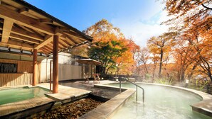 A hot spring area with wooden walkways, a pool, and autumn-colored trees in the background. - Okunikko Hotel Shikisai (Nikko)