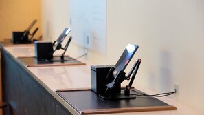 A row of black electronic devices on a wooden table against a plain wall.