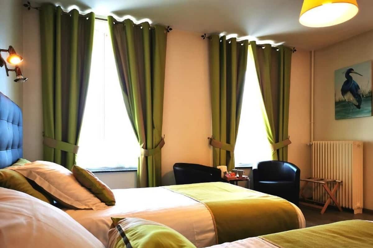 Een hotelkamer met twee bedden, een bureau, een stoel en een radiator.