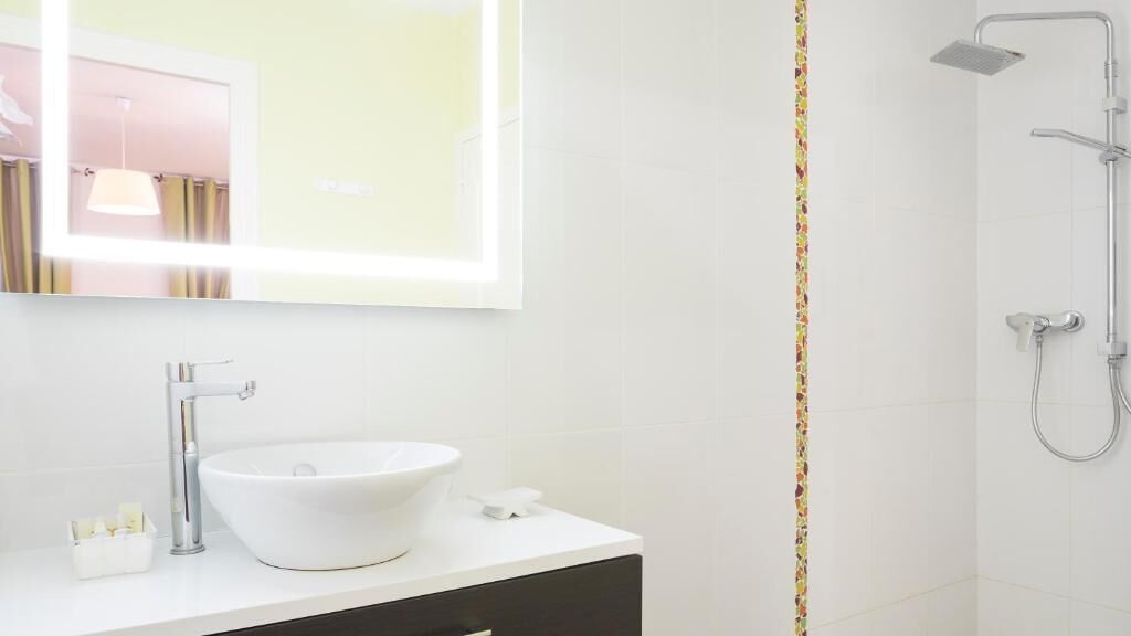 A modern bathroom with a white sink, a mirror, and a shower.