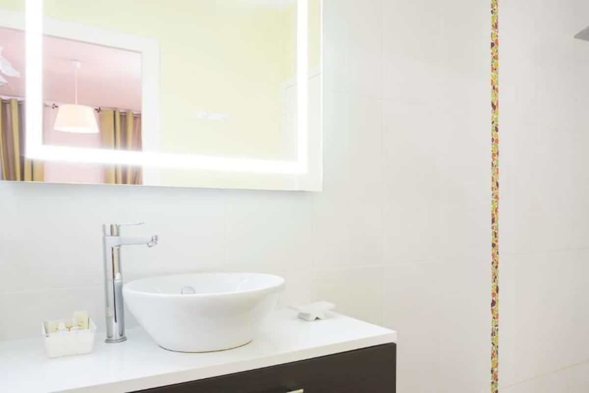 Een moderne badkamer met een wit wastafel, een spiegel en een douche.