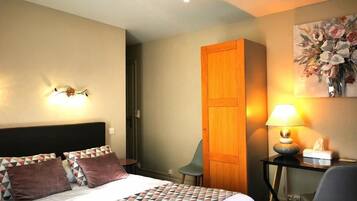 Una habitación de hotel con cama, escritorio, silla, armario y un cuadro en la pared.