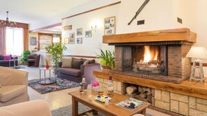Een gezellige woonkamer met een open haard, een bijzettafeltje met drankjes en een bank.