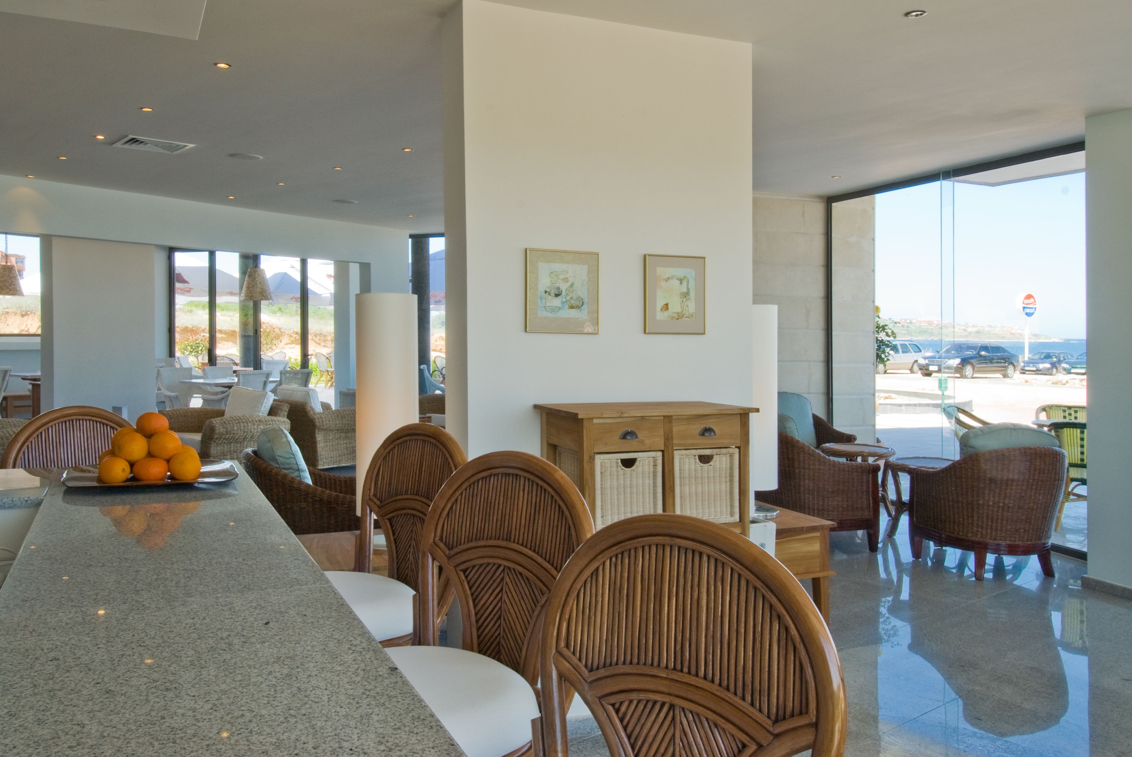 Un comedor moderno con una mesa larga, sillas de mimbre y vistas al exterior.