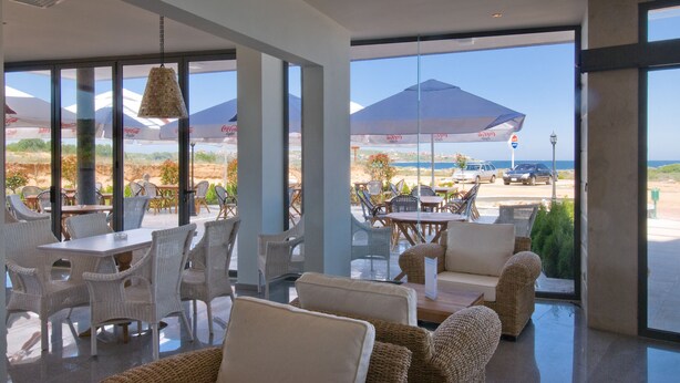 A spacious outdoor seating area with wicker furniture and umbrellas, overlooking a beach and ocean view. - South Pearl Apart Complex (Sozopol)