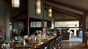 A spacious dining area with a long wooden table set for a meal, surrounded by wicker chairs.