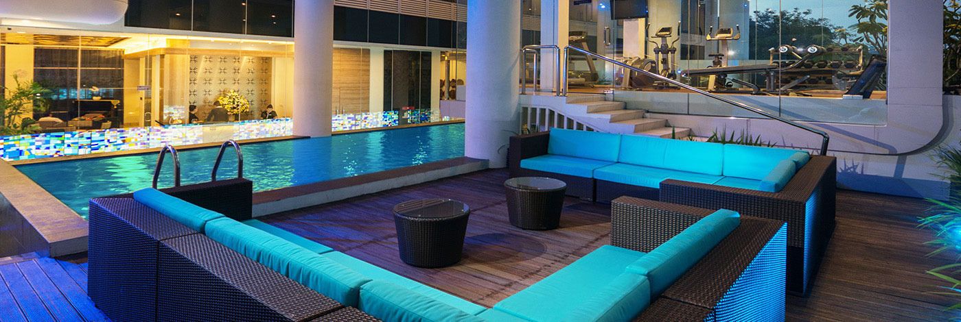 Un espace aménagé au bord de la piscine, avec des sièges et un escalier menant à un niveau supérieur.
