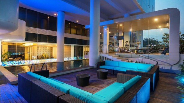 Uma área de estar moderna ao ar livre, com piscina, assentos e escada que dá acesso a um andar superior.