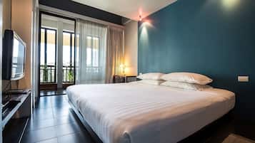 A hotel room with a bed, a TV, a lamp, and a view of the outdoors.
