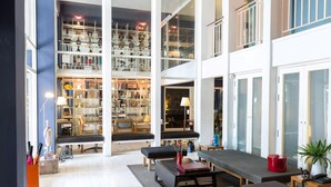 A spacious, well-lit interior with a large open-plan layout, featuring a central seating area, a bookshelf, and a dining table. - LoogChoob Homestay (Bangkok)