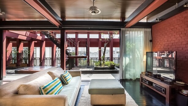 A modern living room with a sofa, ottoman, and TV stand. - LoogChoob Homestay (Bangkok)