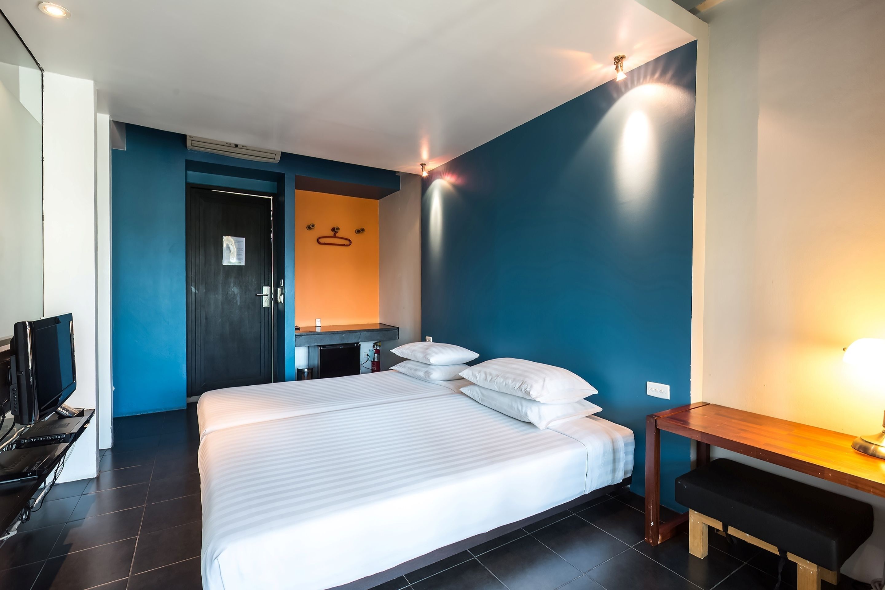 A modern hotel room with a large bed, a desk, and a television.