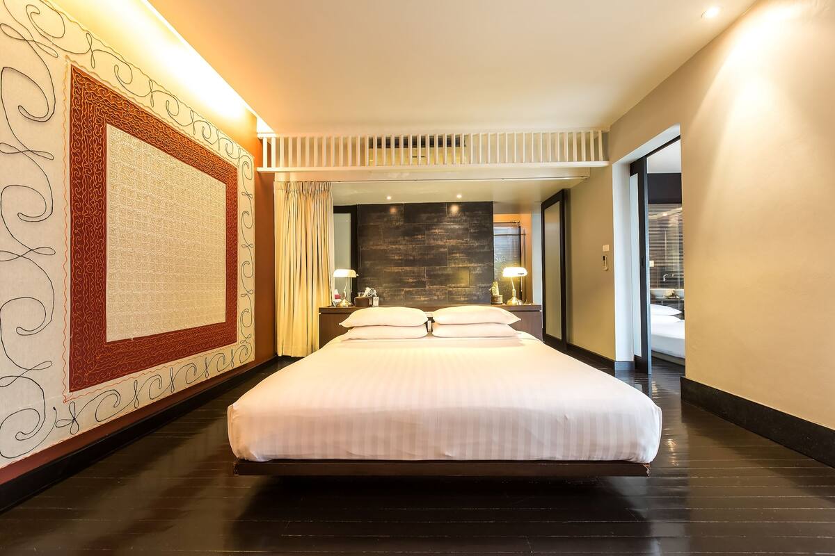 Una habitación de hotel moderna con una cama grande, una pared de acento de piedra y un panel decorativo.