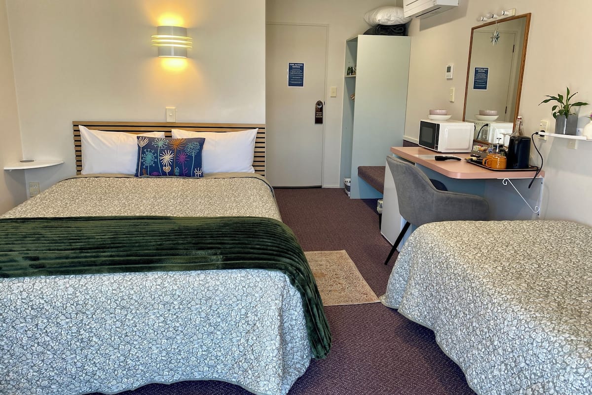 A hotel room with two beds, a desk with a computer, a microwave, and a small seating area.