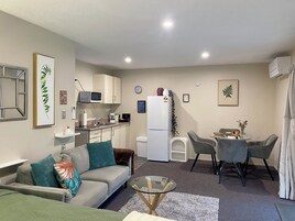 A compact living space with a kitchenette, a sofa, a dining table with chairs, and a small coffee table.