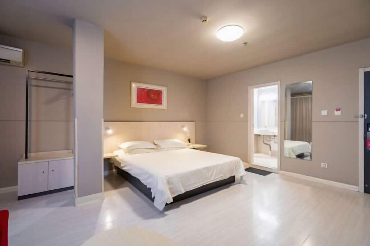 A bedroom with a bed, bedside tables, a wardrobe, and a mirror.