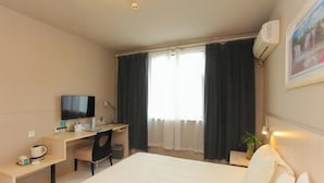A hotel room with a bed, a desk, a chair, a television, and a window with curtains. - Jinjiang Inn (Wuxi Liangxi Road Wanda Plaza) (Wuxi)