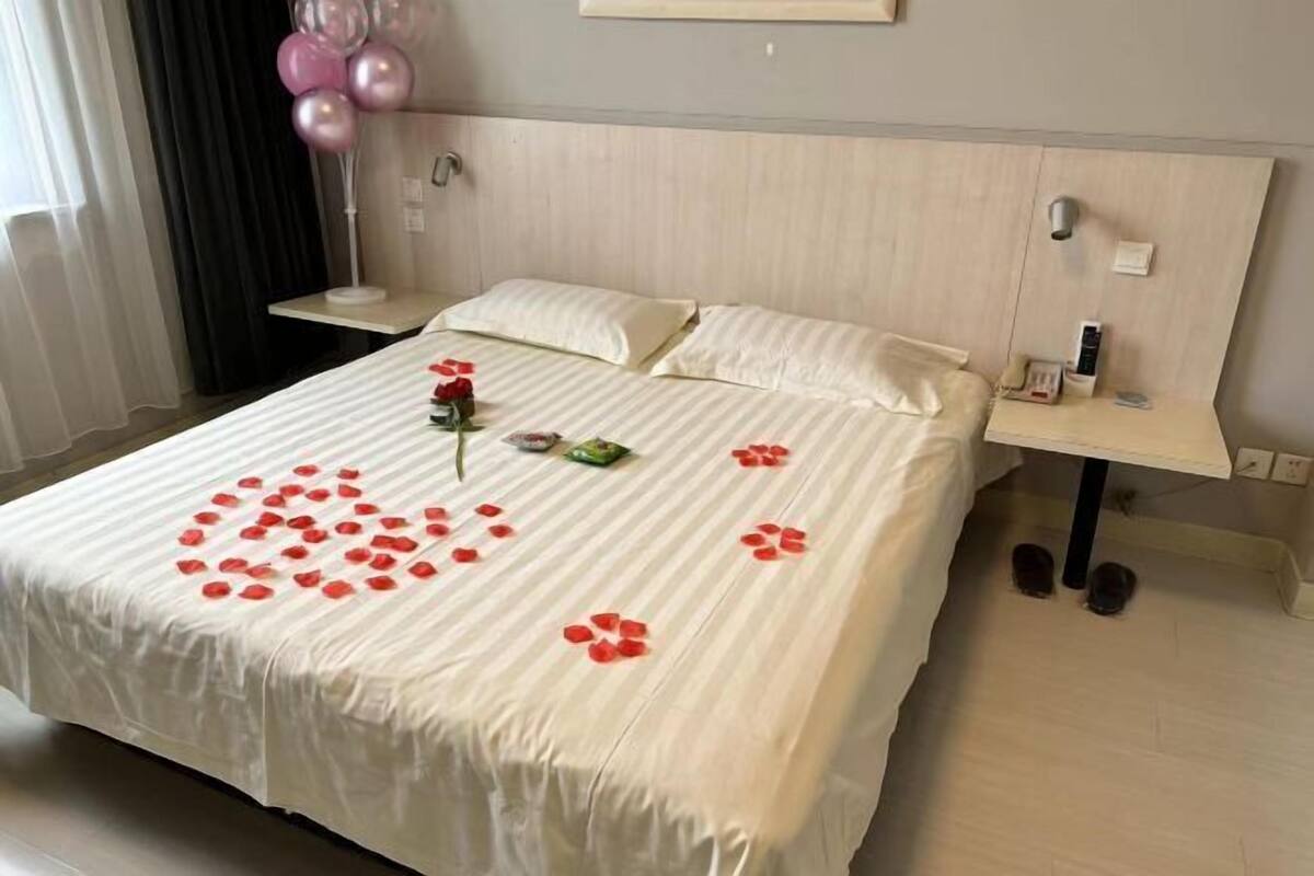 A hotel room with a bed, bedside table, and a nightstand.