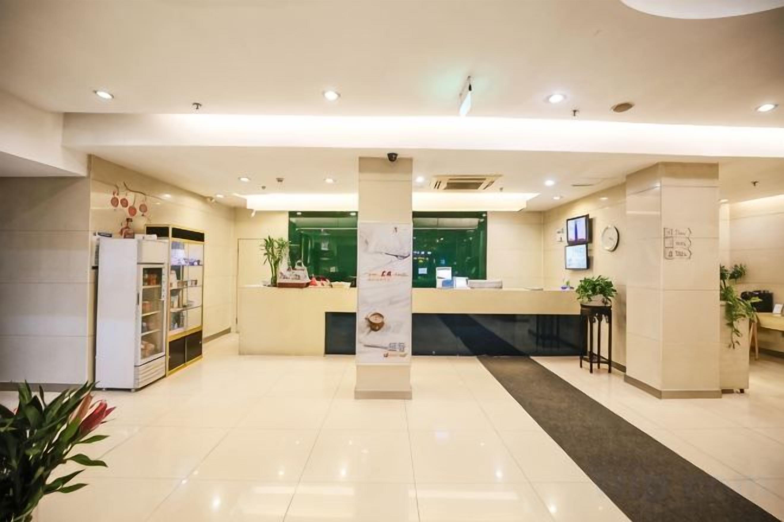 A hotel reception area with a reception desk, a plant, and a clock on the wall.