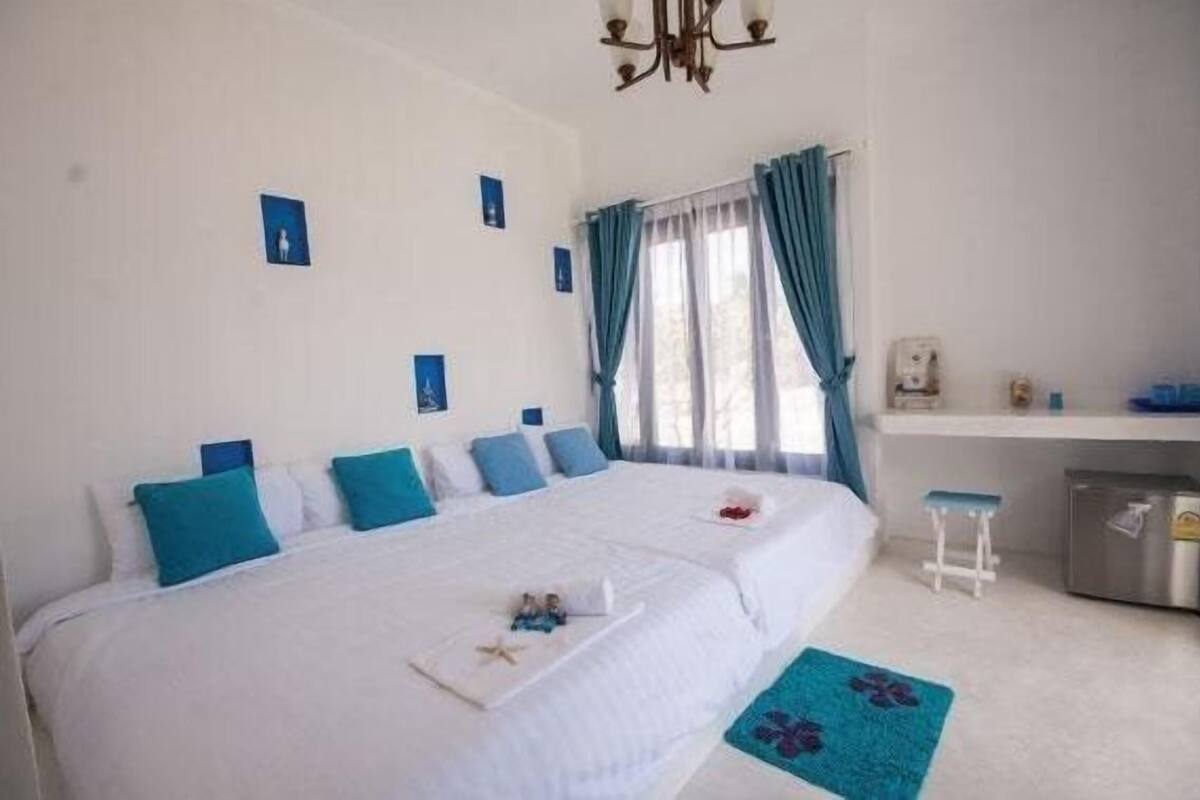 Un dormitorio con cama, escritorio, silla y un taburete pequeño.