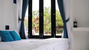 A bedroom with a bed, curtains, and a view of greenery outside. - Laemsing Whitehouse Resort (Laem Sing)