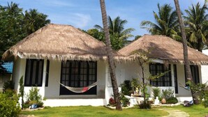 Two thatched-roof huts with white walls and black window frames, surrounded by palm trees and a clear blue sky. - Laemsing Whitehouse Resort (Laem Sing)