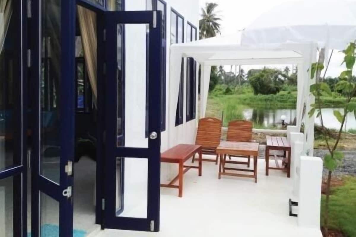 Un área de estar al aire libre con mobiliario de madera y vista a un lago.