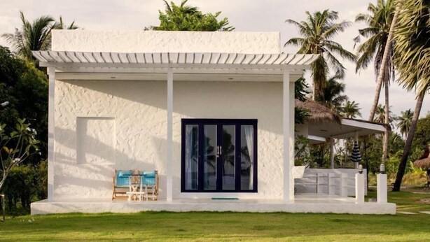 A white building with a covered porch, a large glass door, and a small seating area with a table and chairs. - Laemsing Whitehouse Resort (Laem Sing)