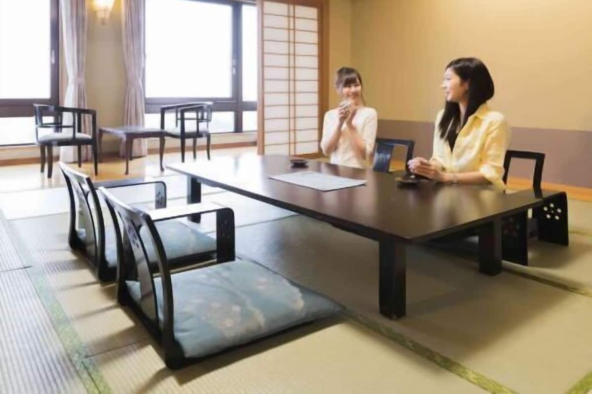 Ein traditioneller japanischer Besprechungsraum mit Tatami-Matten, niedrigen Tischen und Stühlen.
