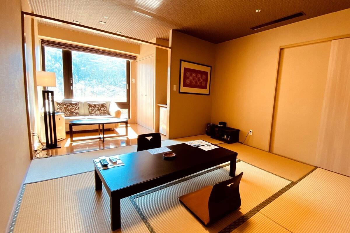 Ein traditioneller japanischer Raum mit Tatami-Böden, einem niedrigen Tisch, einer Couch und einer Schiebetür.